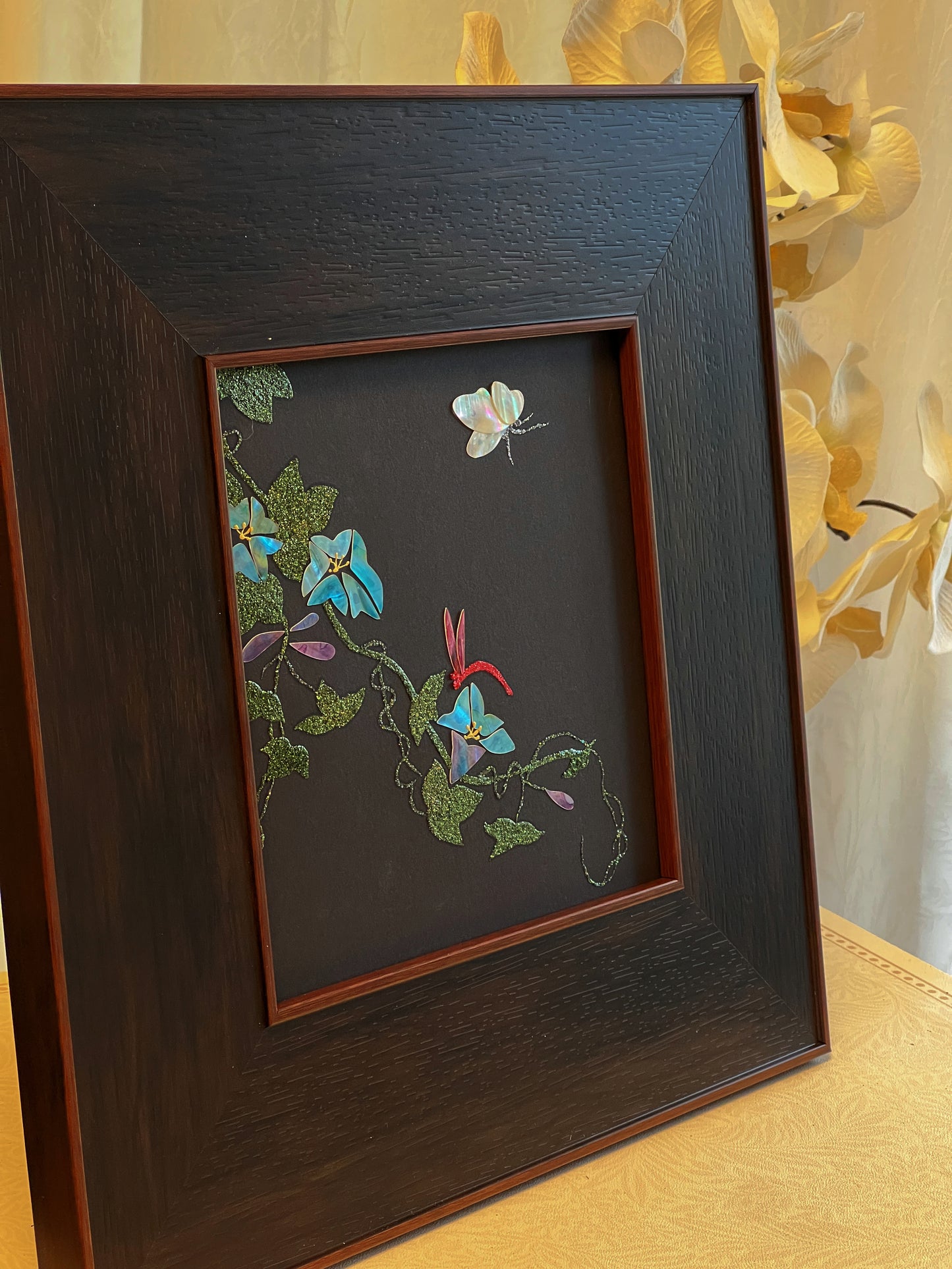 Original Raden shell art titled The Morning Glory by Showing Studio in a 35x35cm wide margin dark walnut frame, showcasing icy blue mother of pearl blossoms, a white shell butterfly, and a crimson dragonfly