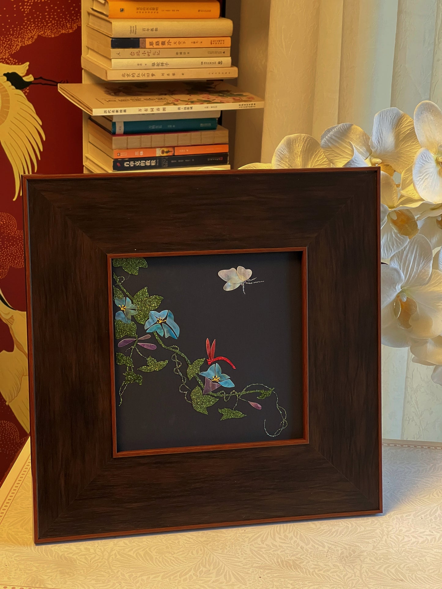 Original Raden shell art titled The Morning Glory by Showing Studio in a 35x35cm wide margin dark walnut frame, showcasing icy blue mother of pearl blossoms, a white shell butterfly, and a crimson dragonfly