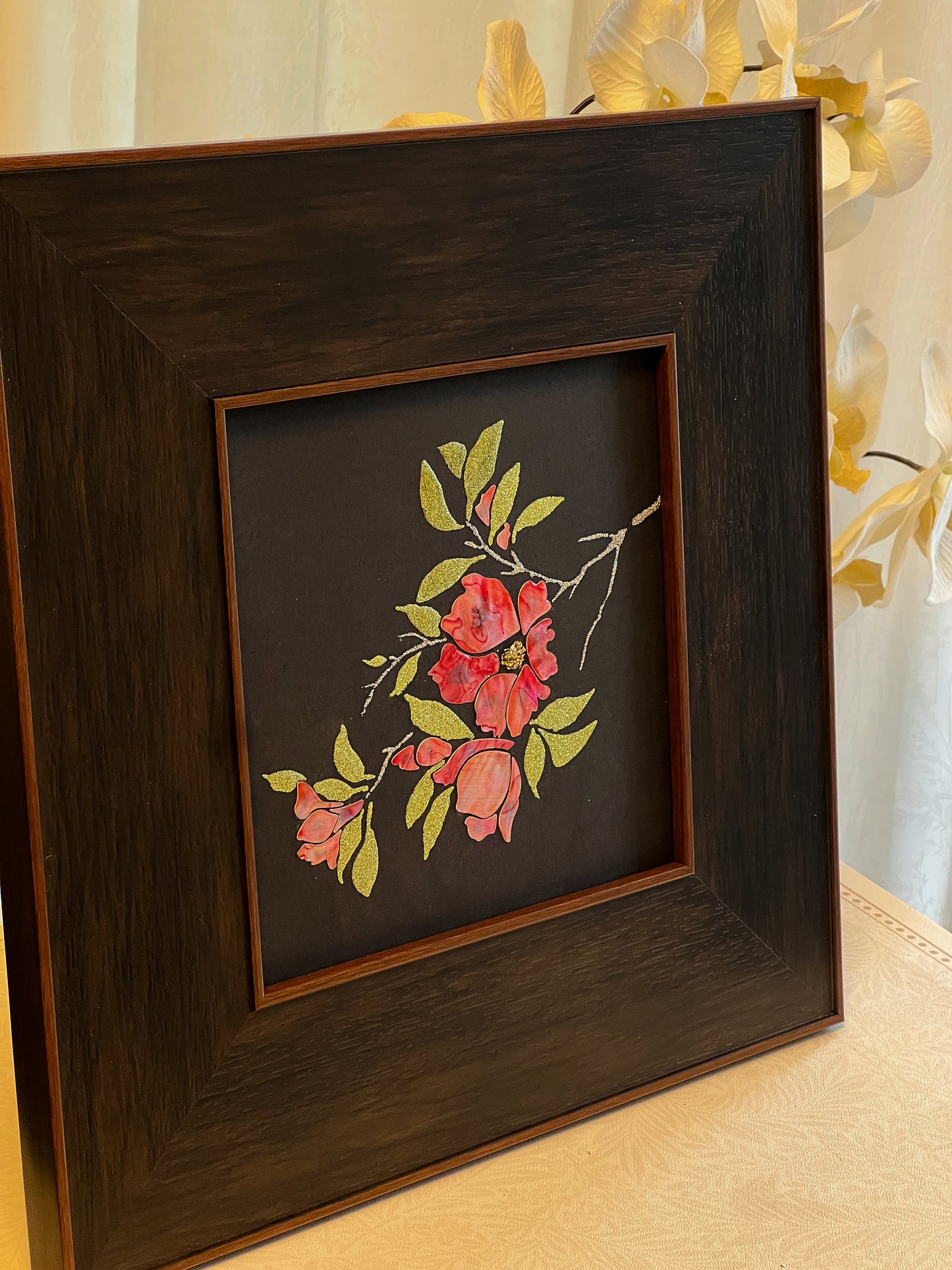 Original Raden shell art titled The Pomegranate Blossom by Showing Studio in a 35x35cm wide margin dark walnut frame, showcasing iridescent crimson mother of pearl petals and gold-lime abalone leaves
