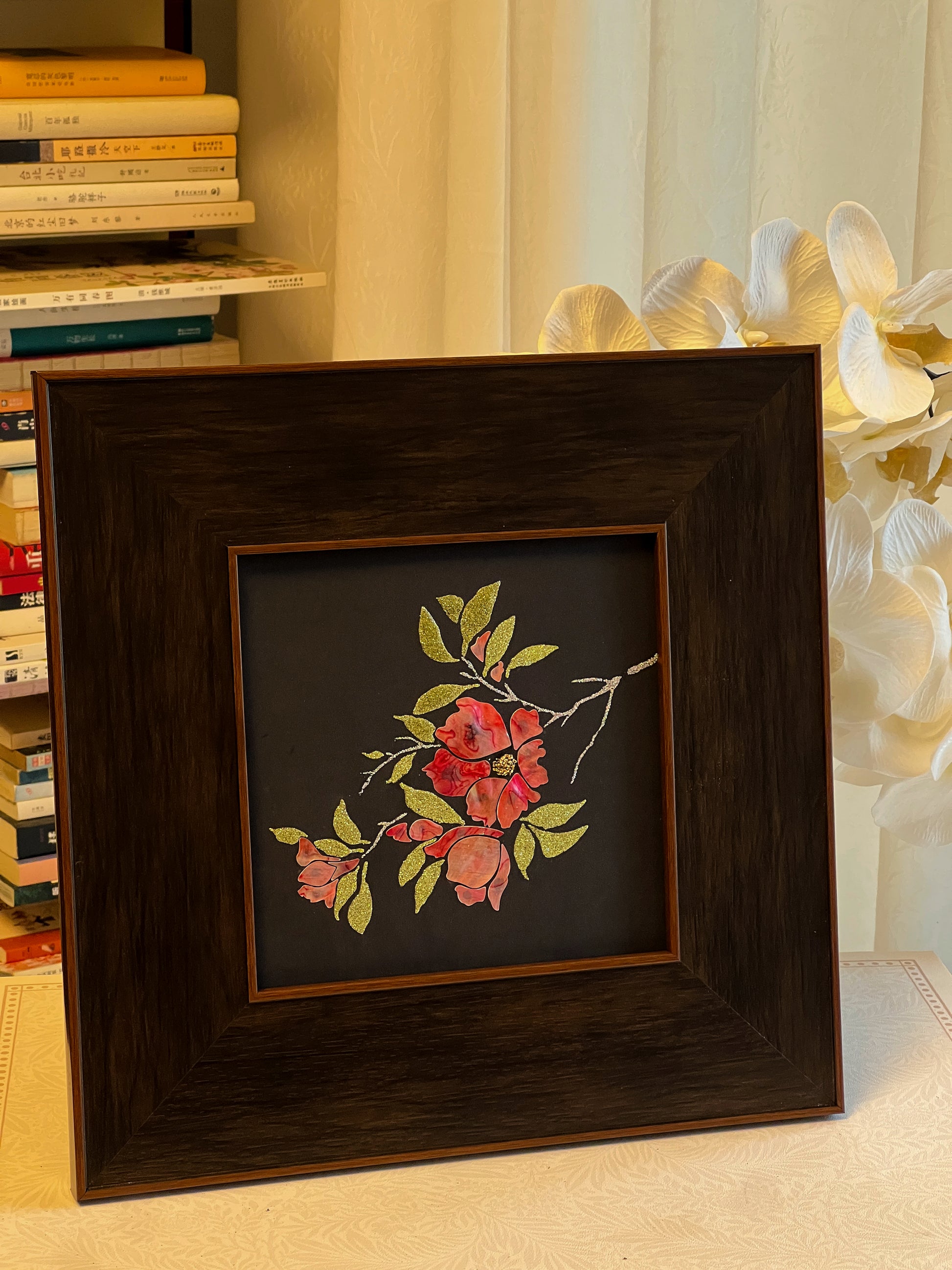 Original Raden shell art titled The Pomegranate Blossom by Showing Studio in a 35x35cm wide margin dark walnut frame, showcasing iridescent crimson mother of pearl petals and gold-lime abalone leaves