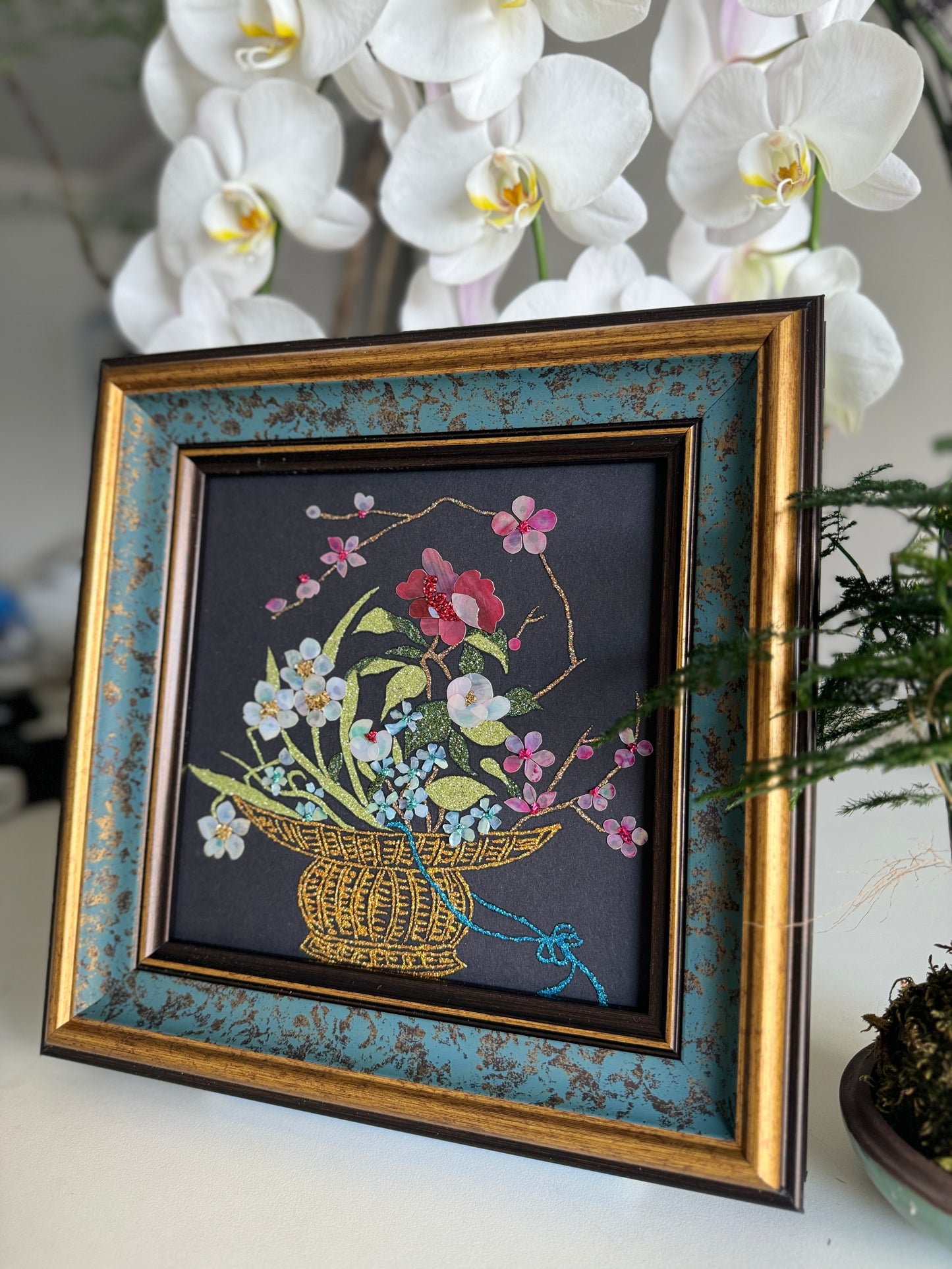 Luxury Zen home decor presentation featuring the "Three Friends of Winter" oriental shell artwork displayed next to a minimalist green kokedama bonsai plant.