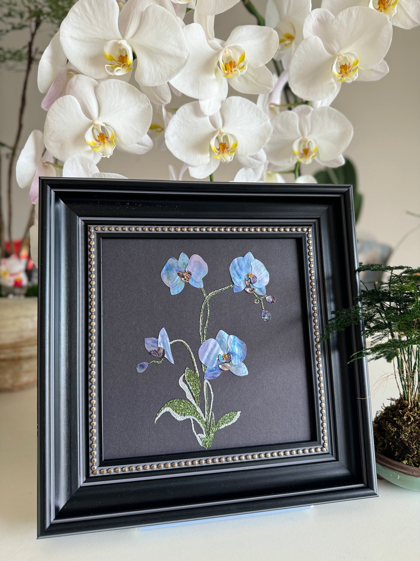 Original abstract Raden shell art titled The Azure Rhythm by Showing Studio in a 29x29cm dark walnut frame, showcasing shimmering green and blue abalone inlay waves on a black background.