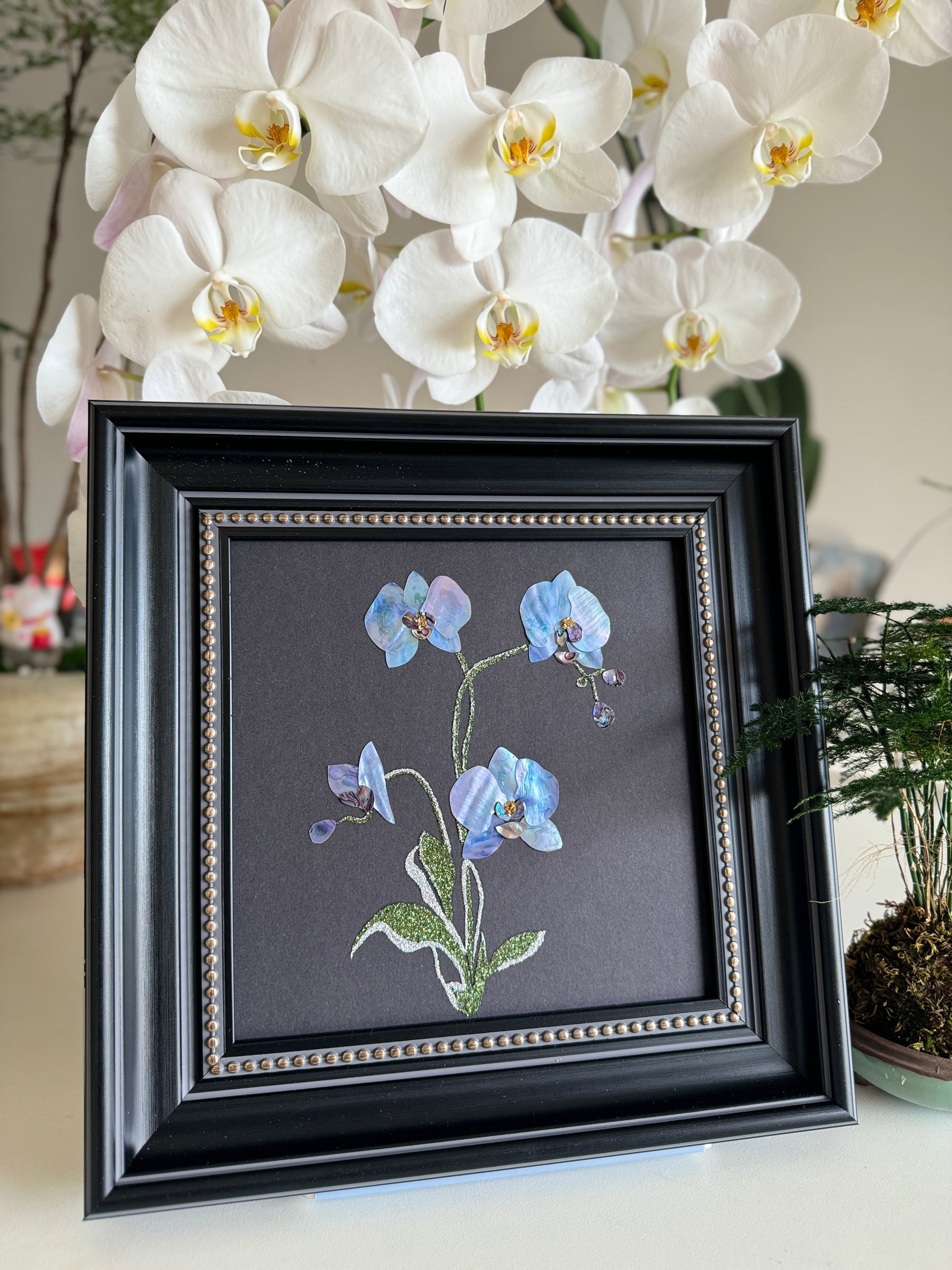 Original abstract Raden shell art titled The Azure Rhythm by Showing Studio in a 29x29cm dark walnut frame, showcasing shimmering green and blue abalone inlay waves on a black background.