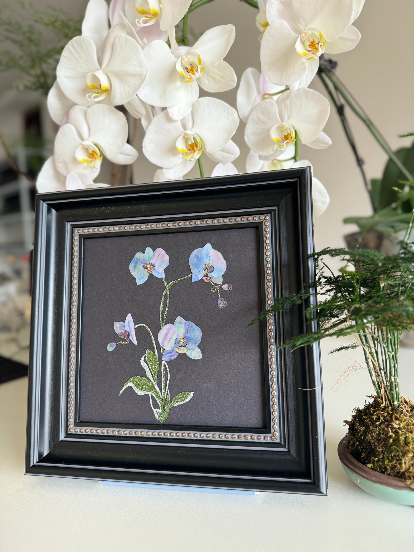 Original abstract Raden shell art titled The Azure Rhythm by Showing Studio in a 29x29cm dark walnut frame, showcasing shimmering green and blue abalone inlay waves on a black background.