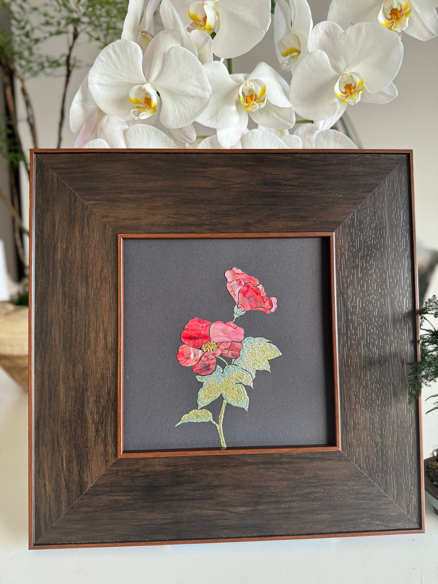 Original Raden shell inlay artwork titled The Cotton Rose by Showing Studio featuring pink mother of pearl petals and shimmering green abalone leaves in a dark walnut square frame.