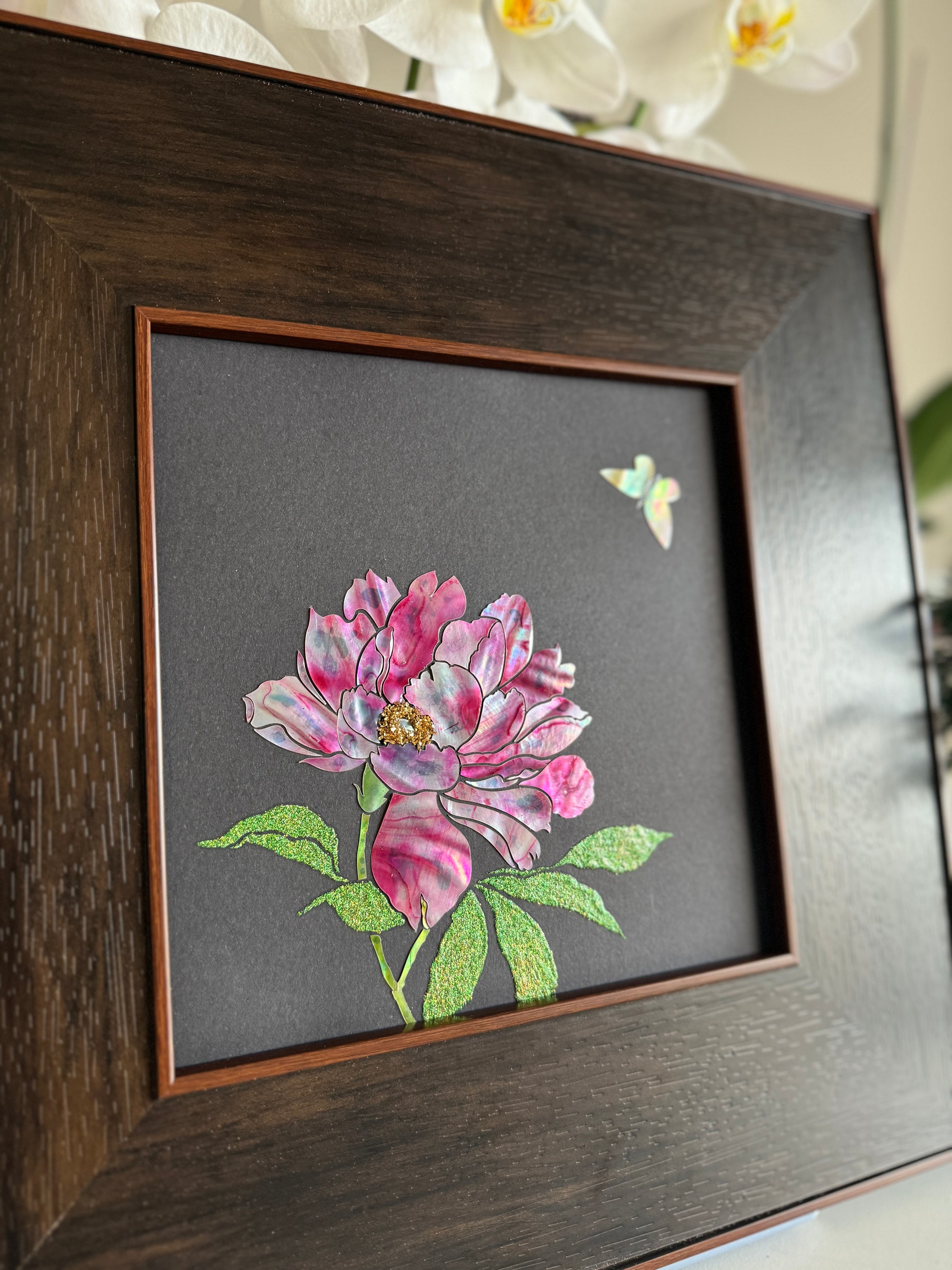 Macro view of traditional Raden lacquer art showcasing the intense pink, gold, and green iridescent luster of hand-cut natural mother-of-pearl peony petals and shimmering butterfly under dynamic lighting.