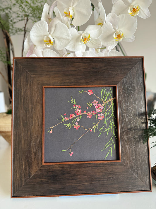 Premium boutique botanical home decor presentation featuring the handcrafted "Smile of Spring" peach blossom shell mosaic painting displayed against a backdrop of elegant white orchids.