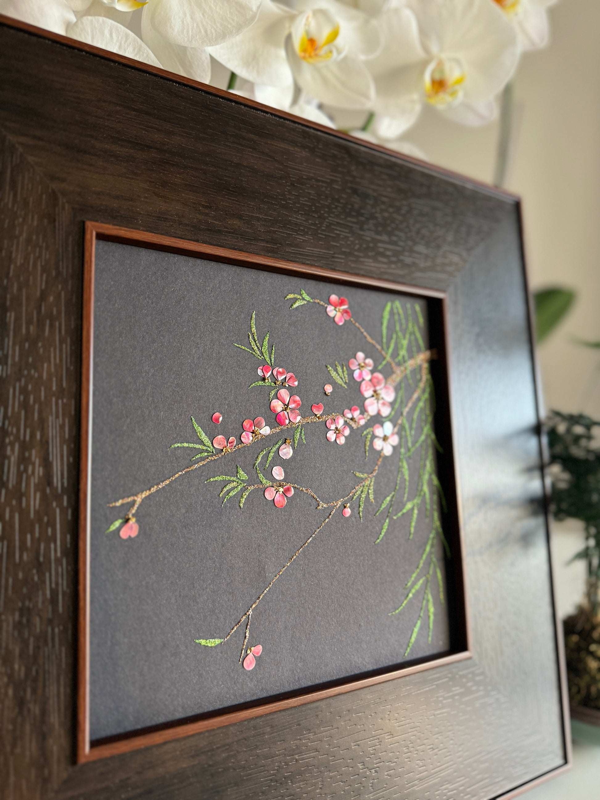 Macro photography of traditional Raden lacquer craftsmanship highlighting the vibrant pink and soft white iridescence of natural shell flower petals and golden glittering branch lines.