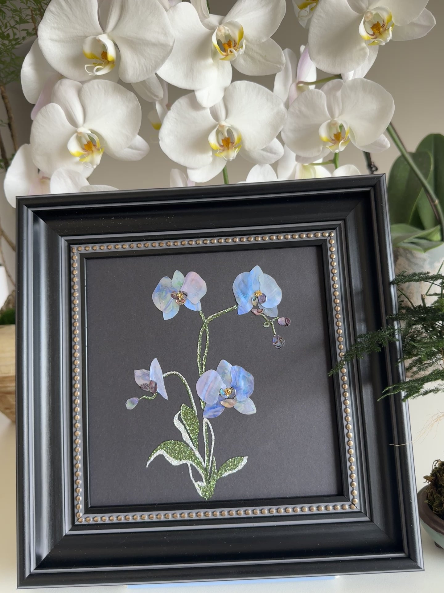 Original abstract Raden shell art titled The Azure Rhythm by Showing Studio in a 29x29cm dark walnut frame, showcasing shimmering green and blue abalone inlay waves on a black background.