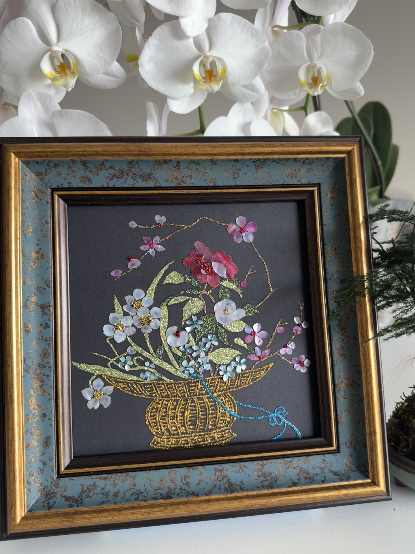 Luxury Zen home decor presentation featuring the "Three Friends of Winter" oriental shell artwork displayed next to a minimalist green kokedama bonsai plant.